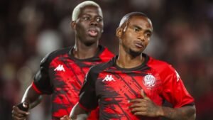 Thembinkosi Lorch and Aziz Ki celebrate in Wydad AC's vibrant red and black kit during a match, showcasing team spirit and determination.