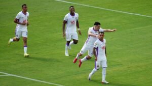 لاعبو الوداد يحتفلون بهدف في الملعب، مرتدين قمصان بيضاء مع لمسات أرجوانية، مما يظهر روح الفريق والإثارة خلال المباراة.