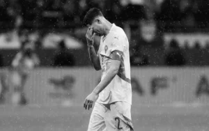 Achraf Hakimi, l'air abattu sous une pluie battante et vêtu du maillot blanc de l'équipe nationale marocaine, après un moment décevant durant le match.