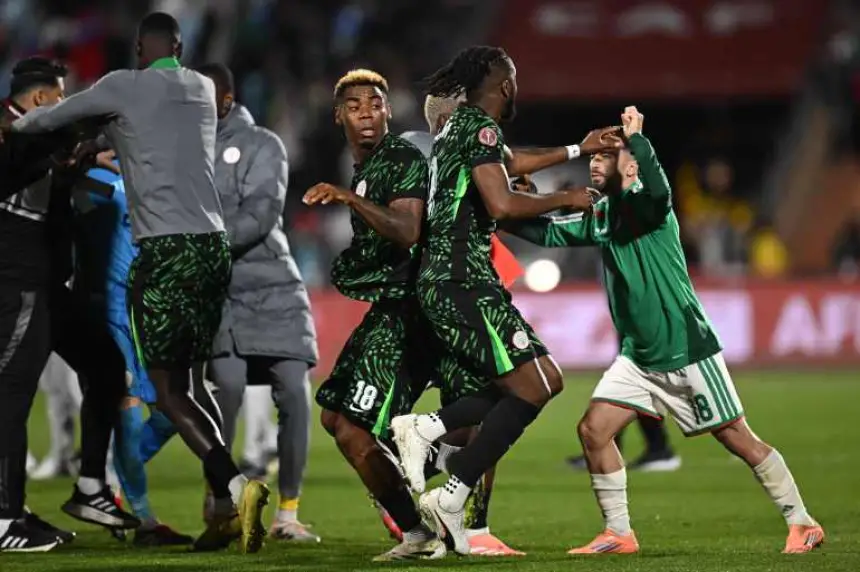 Spanning moment terwijl Nigeriaanse spelers vieren te midden van een schermutseling, gekleed in groene outfits met zwarte patronen, met een Algerijnse speler in het wit.