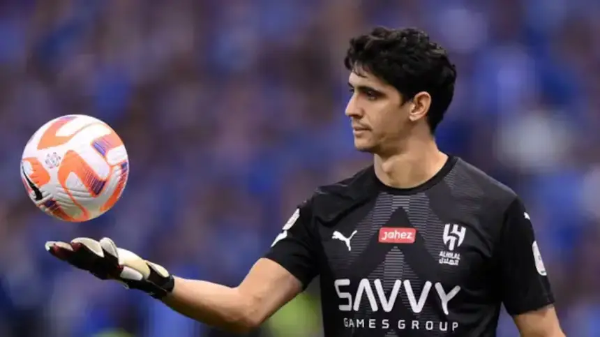 Yassine Bounou, en tenue noire de gardien de but, se tient prêt avec un ballon en main, devant un fond de stade flou pendant un match.