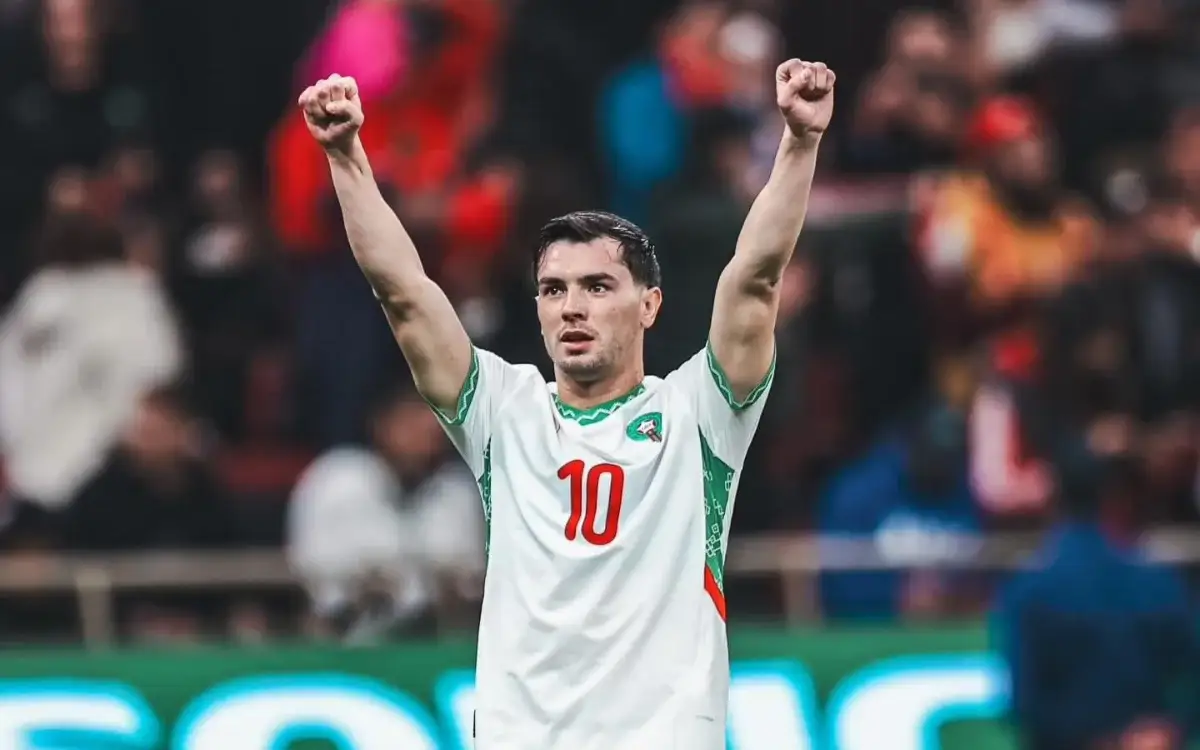 Brahim Diaz celebrates with raised fists, wearing the Moroccan national team jersey featuring the number 10, amidst a vibrant stadium backdrop.