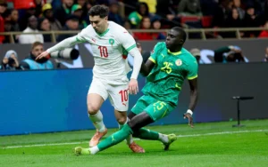 Brahim Diaz (10) du Maroc esquive un tacle du défenseur sénégalais lors d'un match intense, illustrant l'action dynamique du football.