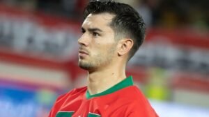 Brahim Diaz, wearing Morocco's red and green national team kit, gazes intently, showcasing his determination during a match.