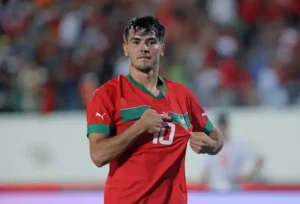 Brahim Diaz célèbre dans le maillot de l'équipe nationale du Maroc, arborant son numéro 10, avec une foule vibrante en arrière-plan.