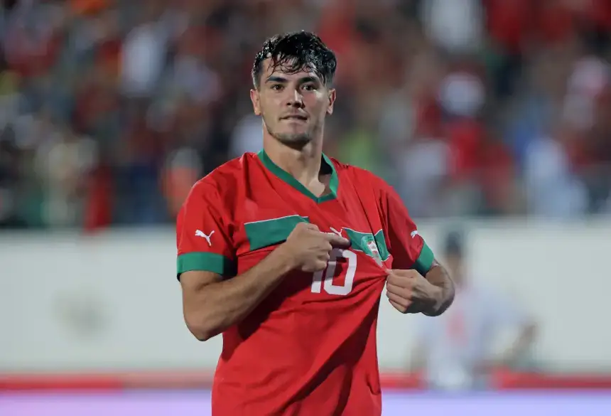 Brahim Diaz célèbre dans le maillot de l'équipe nationale du Maroc, arborant son numéro 10, avec une foule vibrante en arrière-plan.