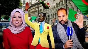 Scène de célébration avec une présentatrice souriante en tenue rouge, un homme en costume jaune, et un reporter masculin, tous entourés de drapeaux algériens.