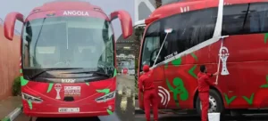 De teambus van Angola, versierd in rood en groen met het Angola-logo en CAF Afrika Cup van Naties branding, wordt schoongemaakt door het personeel.