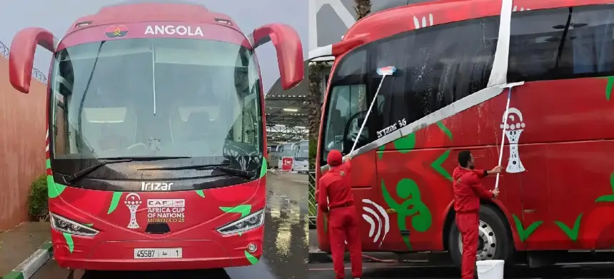 De teambus van Angola, versierd in rood en groen met het Angola-logo en CAF Afrika Cup van Naties branding, wordt schoongemaakt door het personeel.