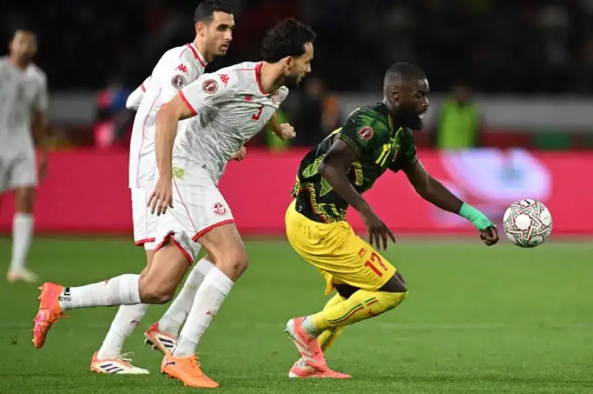 Tunisian players in white gear press against a vibrant green and yellow-clad opponent, chasing the ball during a tense match action.
