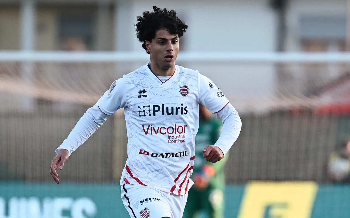 Hachim Mastour in a white football kit with red accents, actively running on the pitch during a match.