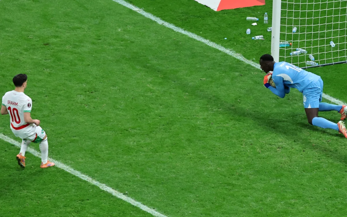 براهيم دياز، مرتديًا القميص رقم 10، يستعد لتسديد ركلة جزاء بنمط "بانينكا" بينما يراقبه حارس المرمى المنافس، في خلفية ملعب أخضر نابض بالحياة.