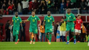 Senegal players in vibrant green kits celebrate on the pitch, showcasing team unity during a tense international match.