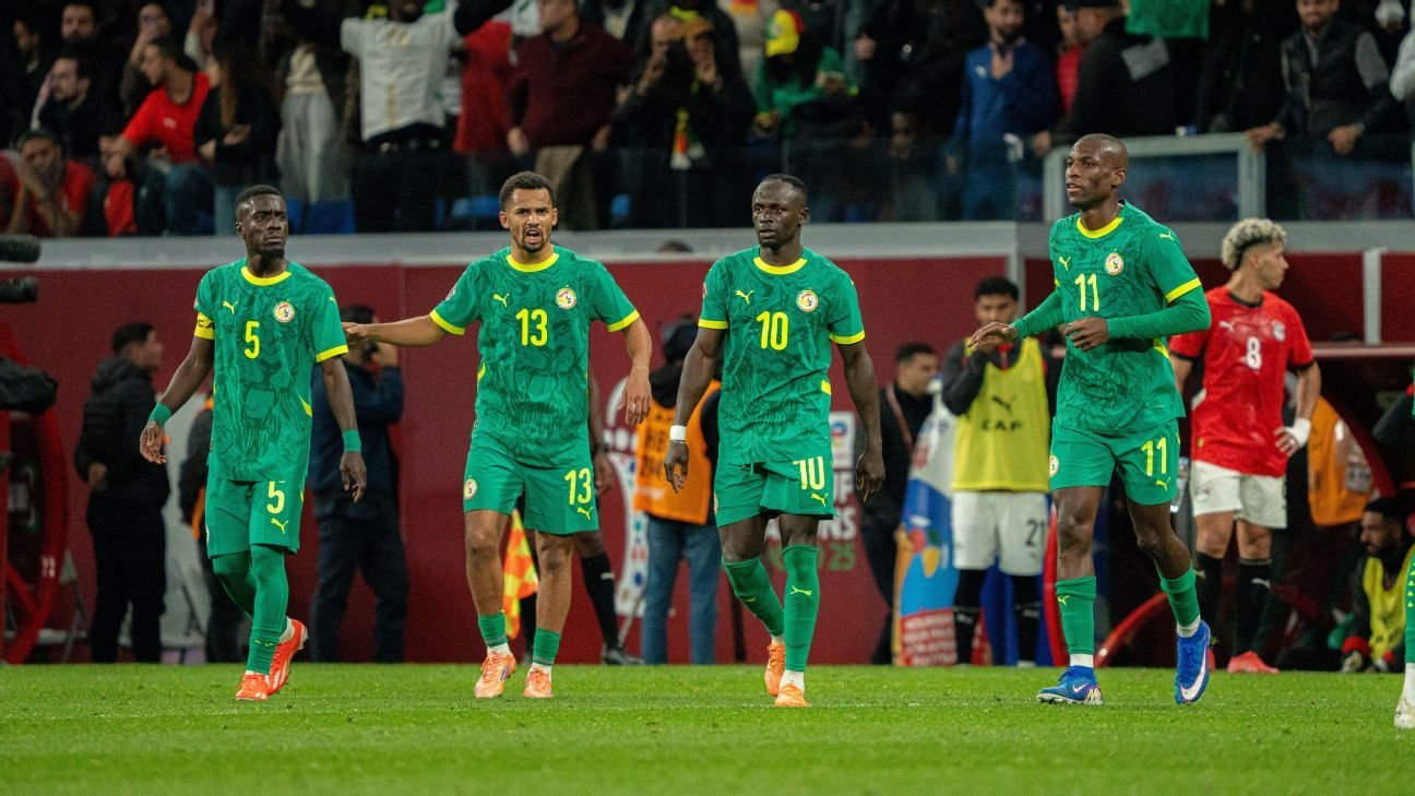 Senegal players in vibrant green kits celebrate on the pitch, showcasing team unity during a tense international match.