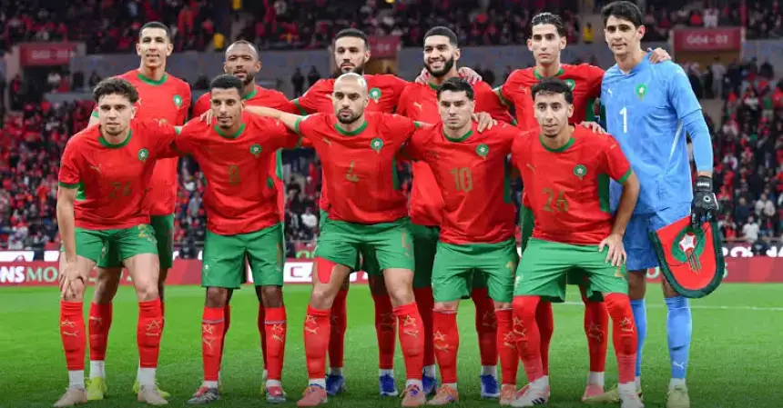 Morocco's national football team poses for a team photo in their red and green kits, showcasing team spirit in a stadium packed with fans.