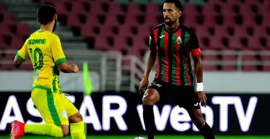 جيش نهالي من شبيبة رليزان يمرر الكرة مرتدياً قميصاً مخططاً بالأخضر والأسود، في مواجهة أيوب يديرن من شبيبة القبائل في مباراة مشحونة.