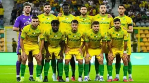 L'effectif du Kabylie FC pose pour une photo d'équipe dans ses tenues jaune et vert vif, avec un gardien de but en violet, dans un cadre de stade.