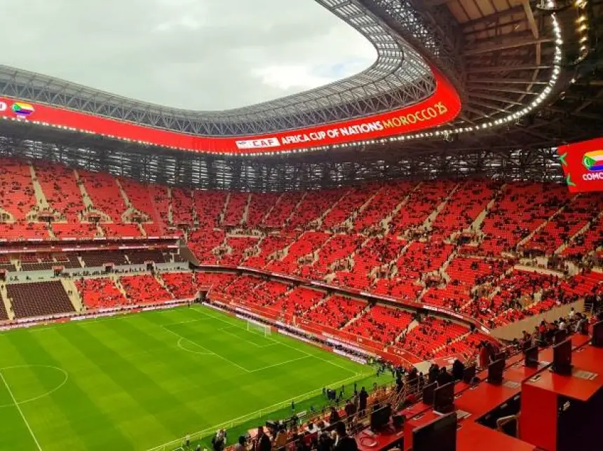 Stadium view during the Africa Cup of Nations, featuring vibrant red seating, a green pitch, and overhead banners for Morocco.