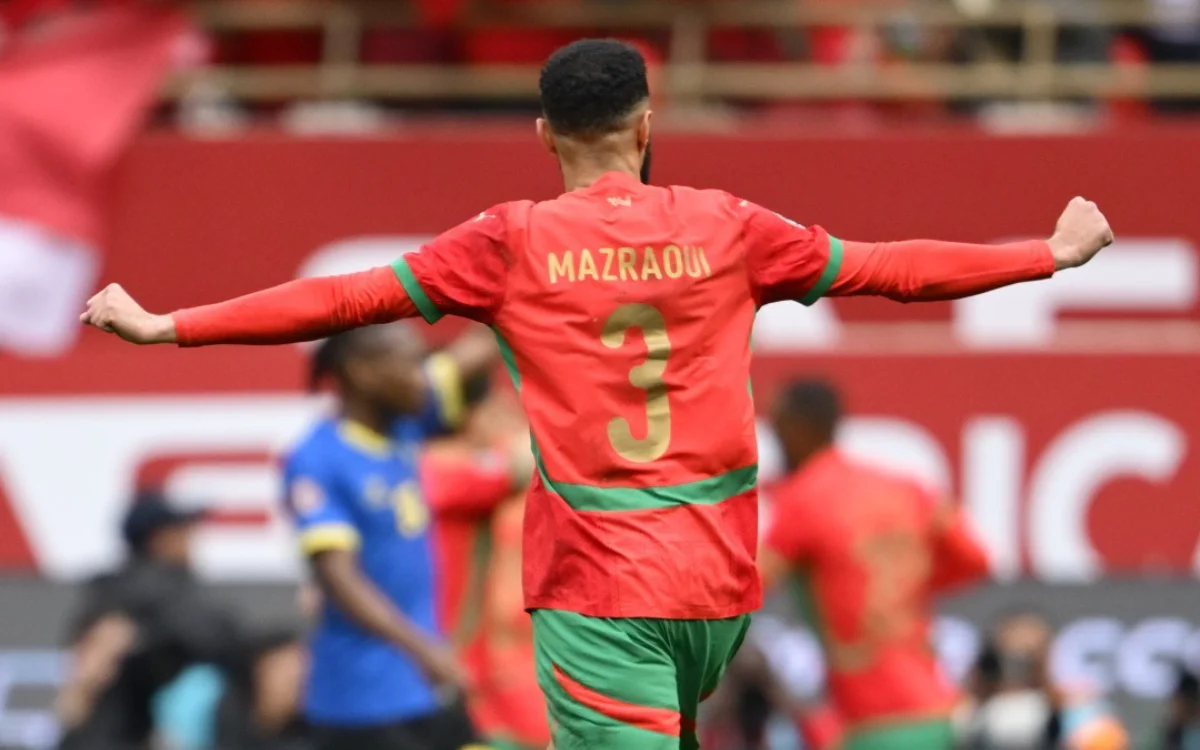 Mazraoui célèbre les bras tendus dans le maillot rouge et vert éclatant du Maroc lors du match de la Coupe d'Afrique 2025.
