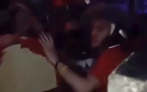 Moroccan supporters celebrating energetically in a café during the Africa Cup final, wearing red jerseys and surrounded by festive decor.