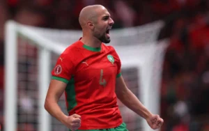 Moroccan player celebrating passionately in a vibrant red kit with green accents during the Africa Cup quarter-finals, 2025.
