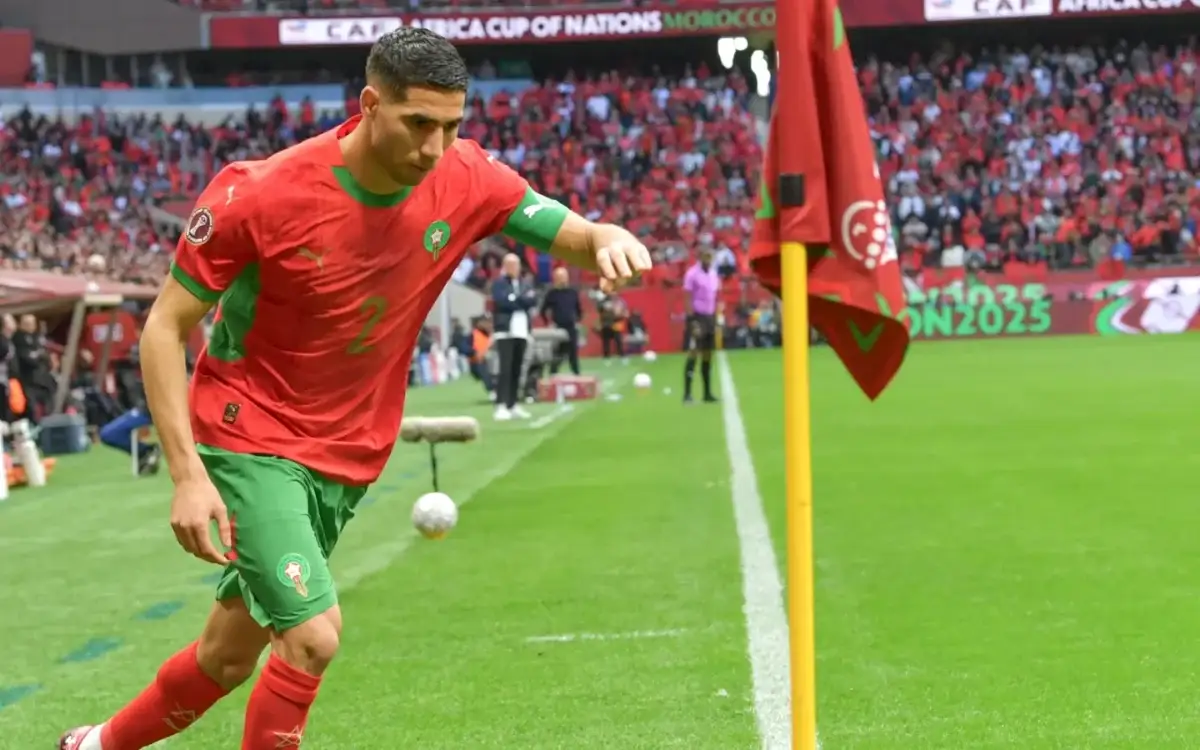Le joueur marocain se prépare à tirer un corner lors de la Coupe d'Afrique des Nations 2025, avec des fans en rouge applaudissant en arrière-plan.
