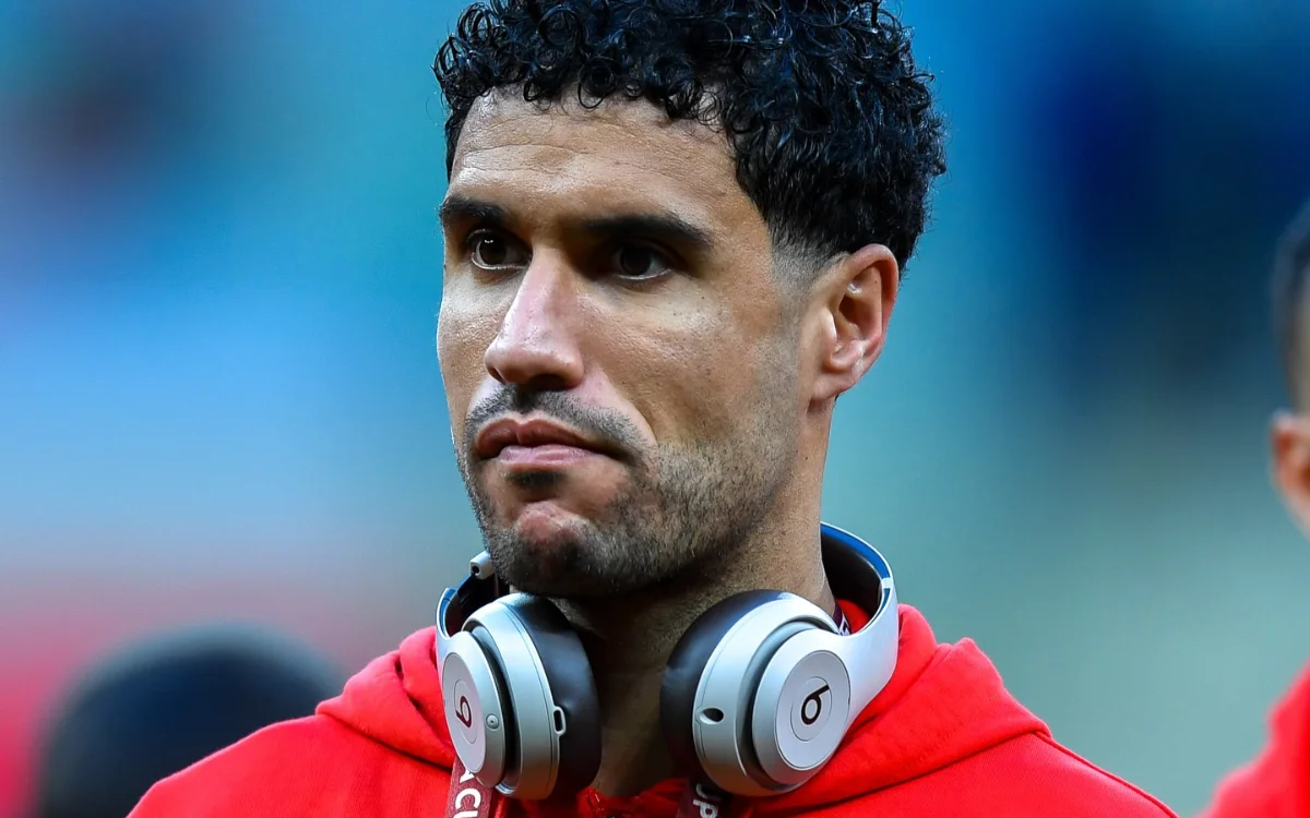 Munir El Kajoui wearing a red hoodie and headphones, displaying a focused expression ahead of a match, reflecting Moroccan football spirit.
