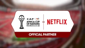 Logo de la CAF Coupe d'Afrique des Nations Maroc 25 aux côtés de l'identité Netflix, mettant en avant leur partenariat en tant que " Partenaire Officiel " sur un fond de stade flouté.