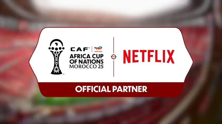 Logo de la CAF Coupe d'Afrique des Nations Maroc 25 aux côtés de l'identité Netflix, mettant en avant leur partenariat en tant que " Partenaire Officiel " sur un fond de stade flouté.
