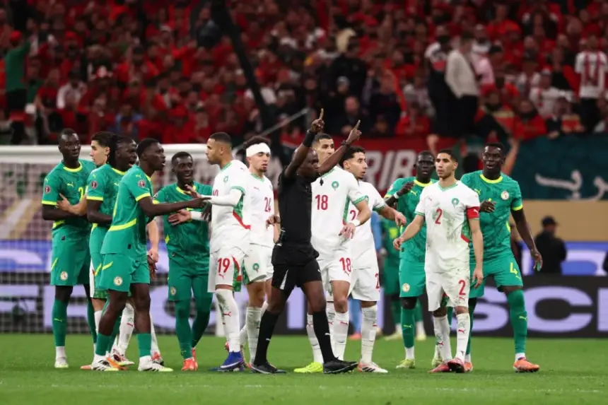 Morocco and Senegal players in heated discussion with the referee during a tense moment in a match, set against a vibrant crowd backdrop.