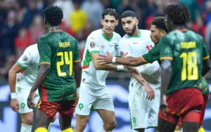 Morocco players in white jerseys discuss with Cameroon opponents in green during a tense moment in their recent match.