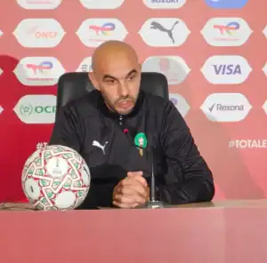 Walid Regragui s'adresse à la presse lors d'une conférence, un ballon aux couleurs du football marocain distinctif posé sur la table.