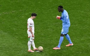 Brahim Diaz, en tenue du Maroc, se tient devant le gardien sénégalais Édouard Mendy, concentré sur le ballon lors d'un moment intense du match.