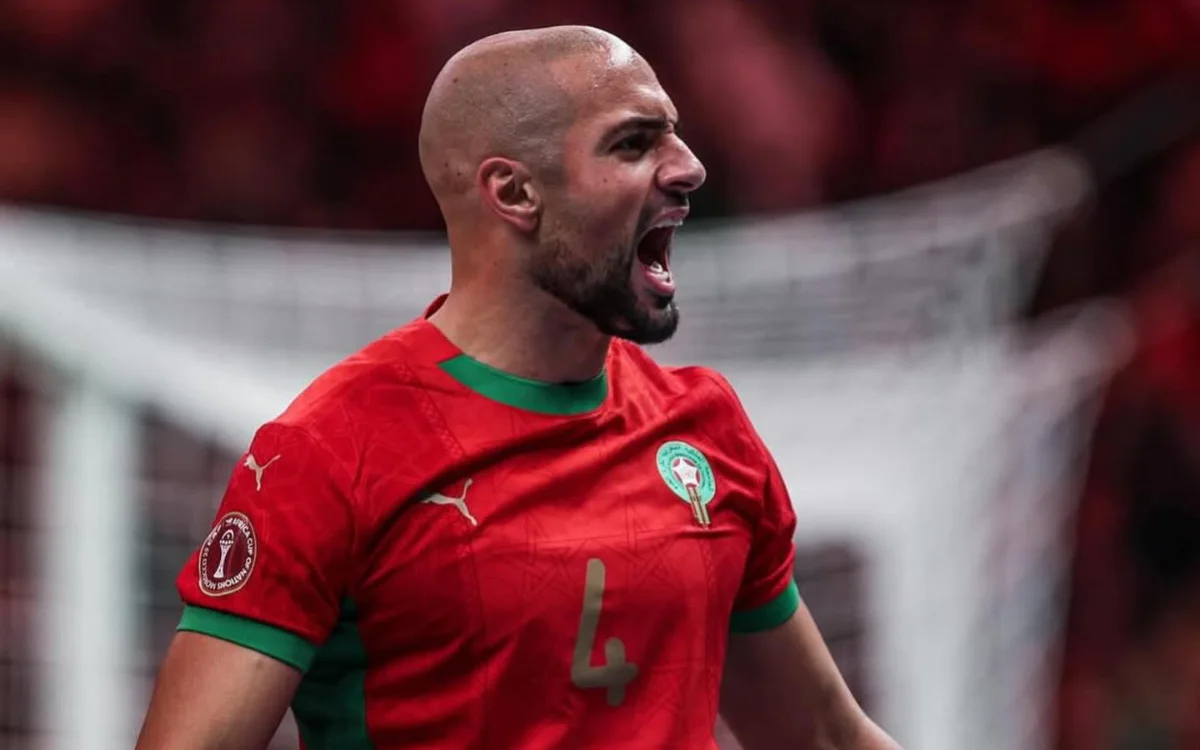 Sofyan Amrabat célèbre avec passion dans le maillot rouge du Maroc, affichant sa fierté lors d'un moment intense de match.