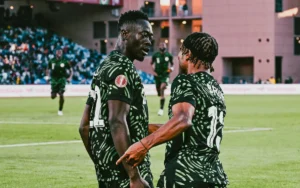 Les joueurs nigérians célèbrent sur le terrain, portant des maillots verts vifs avec des motifs noirs, lors d'un match contre le Maroc.