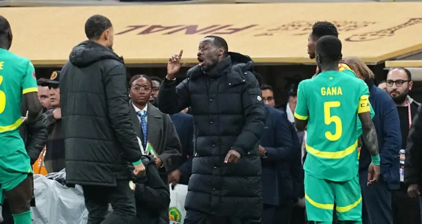 Senegal's coach passionately discusses tactics with players during a tense moment on the sidelines, showcasing team unity and focus.
