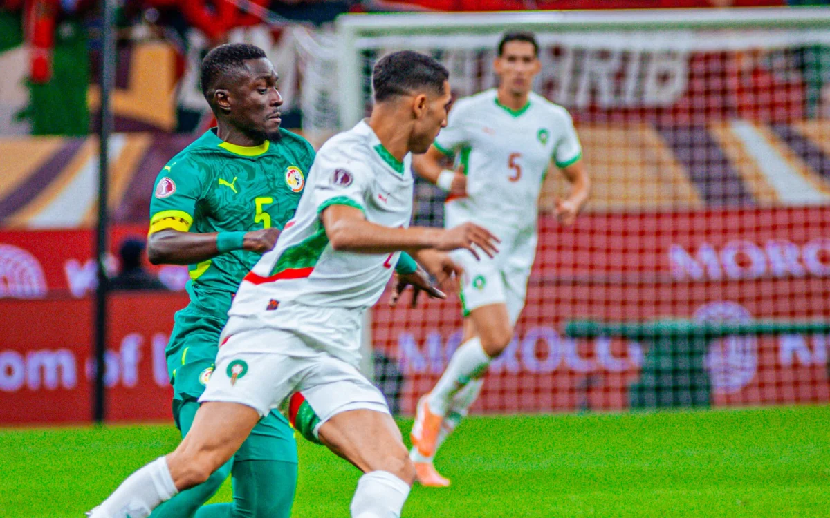 Senegalese player in green clashes with Moroccan player in white during a tense match, showcasing the intensity of African football rivalry.