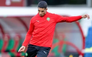 Walid Regragui trains in a red Morocco track suit, showcasing his concentration as he prepares for the upcoming match against Tanzania.