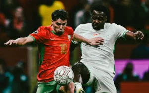 Un joueur marocain portant le numéro 10 s'oppose à un adversaire nigérian, illustrant une compétition intense lors d'un match aux tenues éclatantes.