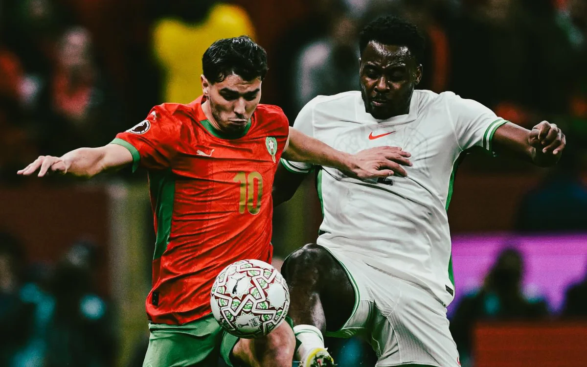 Un joueur marocain portant le numéro 10 s'oppose à un adversaire nigérian, illustrant une compétition intense lors d'un match aux tenues éclatantes.