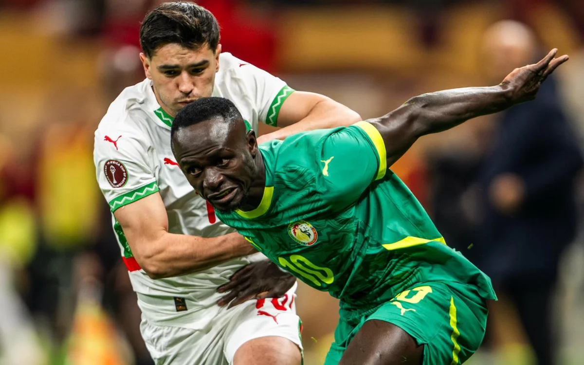 Marokkaanse en Senegalese spelers strijden om balbezit tijdens een intensief moment in de AFCON-wedstrijd, waarbij de teamkleuren en vastberadenheid worden getoond.