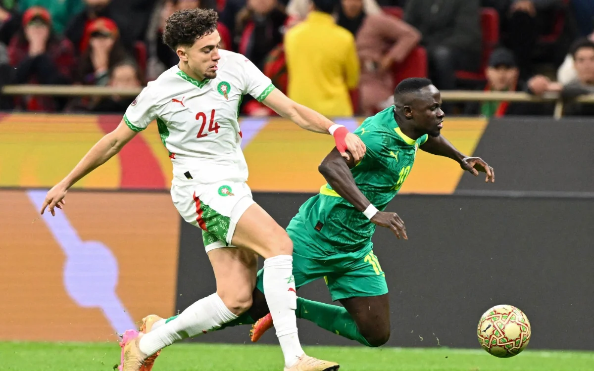 Moroccan player wearing number 24 challenges a Senegalese opponent in a vibrant stadium during an intense match.