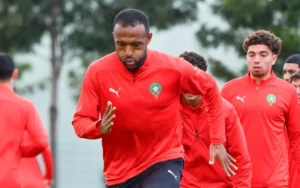 Moroccan players in red Puma training kits, focused on drills, with lush greenery in the background, preparing for their match against Tanzania.