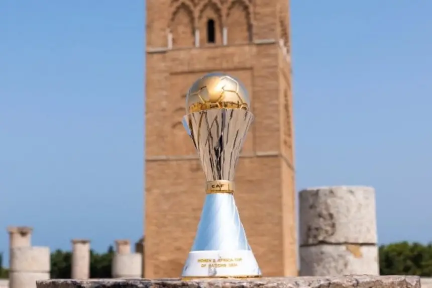 CAF Women's Africa Cup of Nations trophy set against a historic tower in Morocco, showcasing the tournament's significance in Moroccan football.