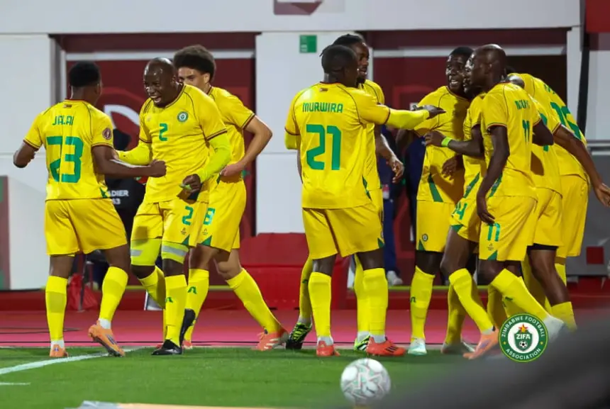Moroccan players celebrate a goal, donned in vibrant yellow jerseys, showcasing teamwork during a match at a stadium.
