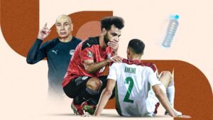 Egyptian coach and players discuss strategy, featuring Mohamed Salah supporting Ashraf Hakimi, with a water bottle in the background.