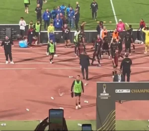 Juichende spelers op het veld na een CAF Champions League-wedstrijd, omringd door fans en de opwinding van de overwinning.