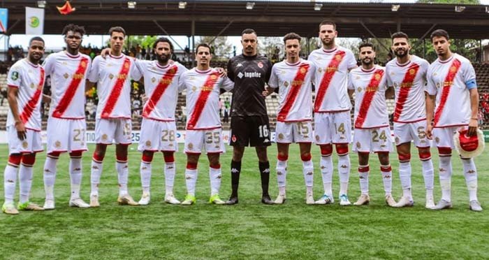 Wydad Casablanca players line up for a team photo, showcasing their red and white kits, with goalkeeping attire in black.