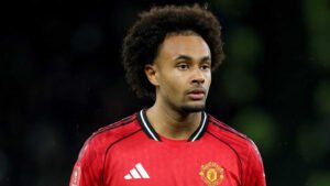 Un ailier portant le maillot rouge de Manchester United, concentré pendant un match, mettant en valeur ses cheveux bouclés distinctifs et son expression déterminée.