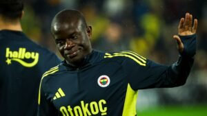 N'Golo Kanté in een Fenerbahçe-trainingspak, lachend en zwaaiend, toont de teamkleuren marineblauw en geel.